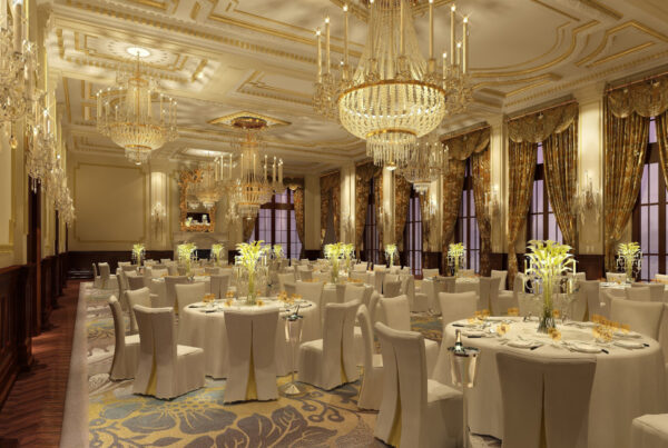 Elegant banquet hall with round tables, covered chairs and chandeliers set for an event