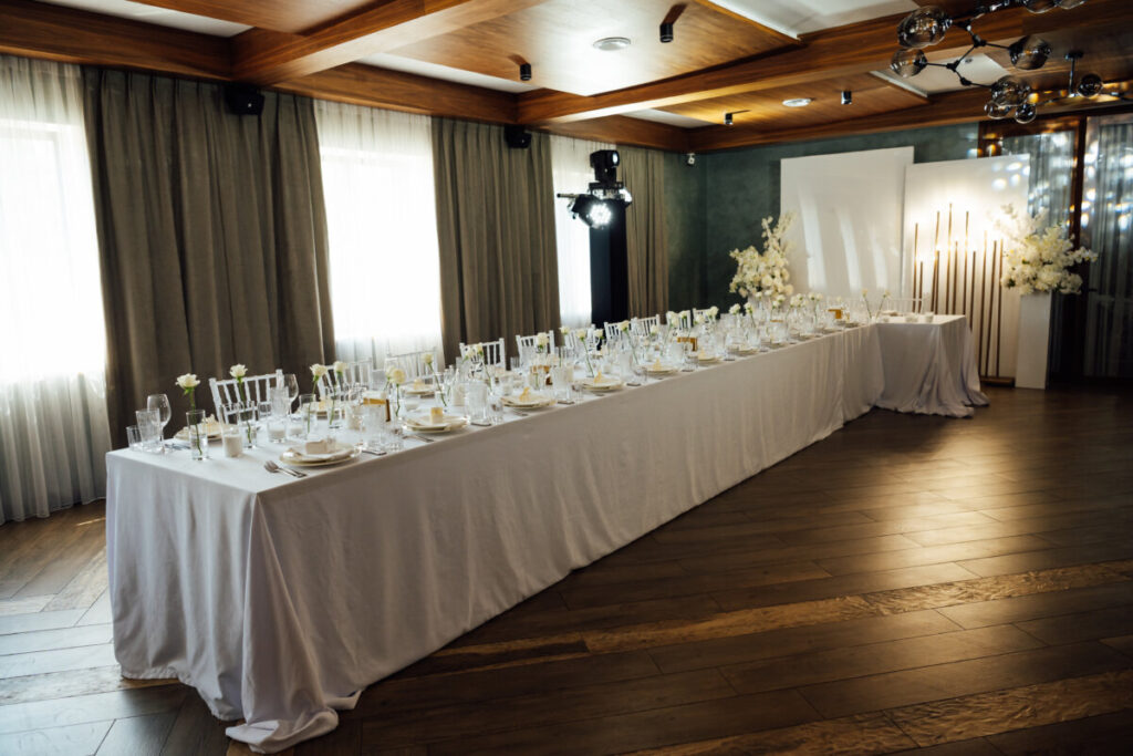 Long banquet table with floor-length white tablecloth set for a wedding reception